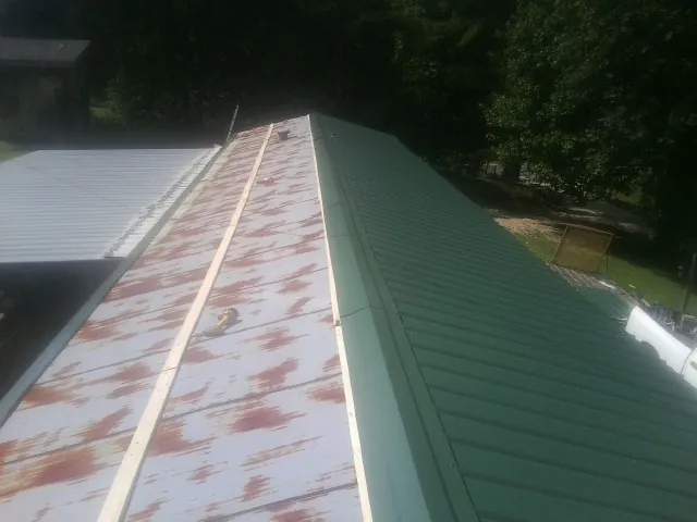 Old rusted panels beside newly installed green metal roofing — Wind Damage Roof Repair by Roofing Brothers in College Grove
