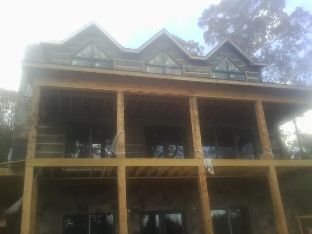 Dormers and porch framing on a large log home under construction — Roof Coating work by our crew in College Grove