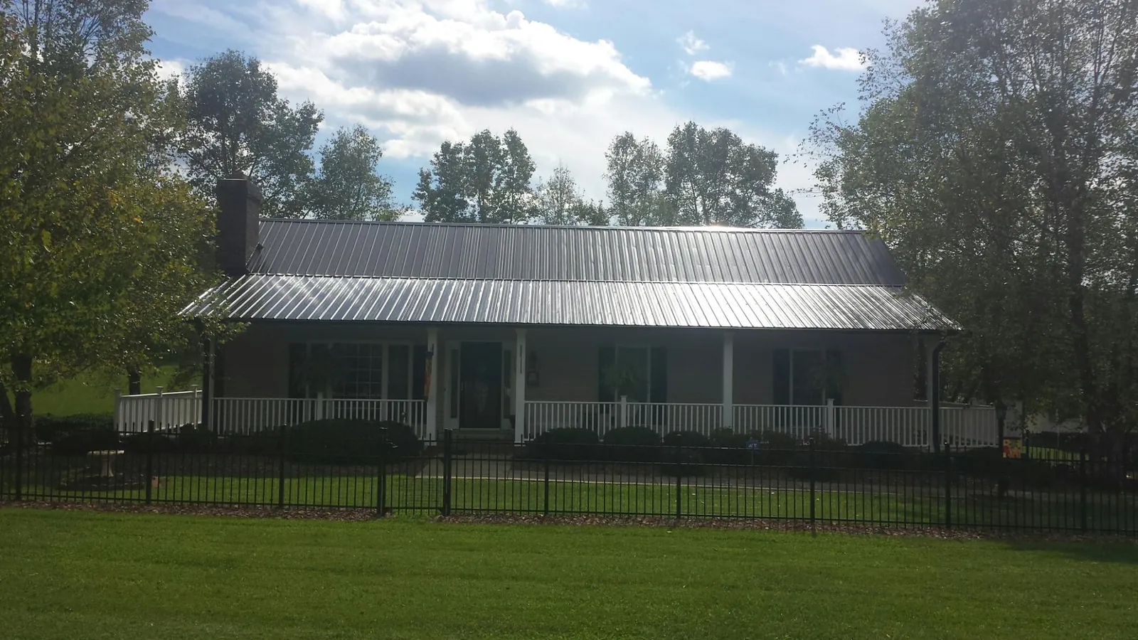 Gray metal roof on a brick ranch with a full width front porch — Gutter Guard Installation work by our crew in College Grove